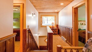 A wooden staircase with a bench, a window with a view, and a door leading to a room with a bed. - Cozy 3Bedroom w/2 Bath and Full Kitchen, Outdoor BBQ, Fire Pits (Lake Placid)