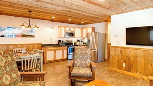 A modern kitchen with wooden cabinets, stainless steel appliances, and a dining area with a patterned chair. - Cozy 3Bedroom w/2 Bath and Full Kitchen, Outdoor BBQ, Fire Pits (Lake Placid)