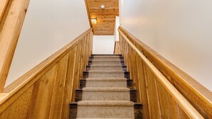 A wooden staircase with carpeted steps leading upwards, flanked by wooden railings. - Cozy 3Bedroom w/2 Bath and Full Kitchen, Outdoor BBQ, Fire Pits (Lake Placid)