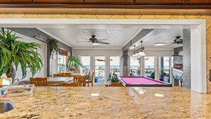 A spacious kitchen with granite countertops, wooden cabinets, and a pool table.