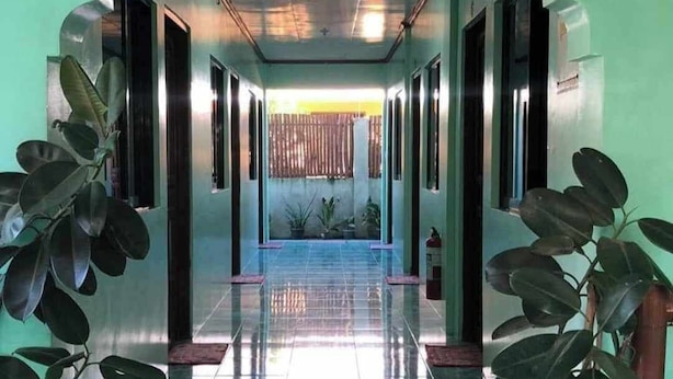 Un couloir doté d’un sol carrelé, de plantes en pot et de portes donnant accès aux différentes pièces.