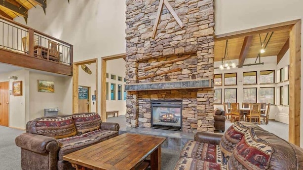 Ein gemütliches Wohnzimmer mit Kamin aus Stein, Ledersofas und einem Holztisch.