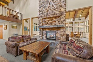 A cozy living room with a stone fireplace, leather sofas, and a wooden coffee table.