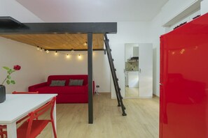 A compact living space with a red sofa, a white table, a ladder, and a red cabinet. - Check in information:You won’t need to meet anyone to access the apartment. Before arrival, you will receive a link to access the Guest Portal, where you can complete the self check-in directly from your phone by entering the ID details of all guests a (Milan)