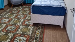 Un dormitorio con una cama, una silla y una alfombra estampada.