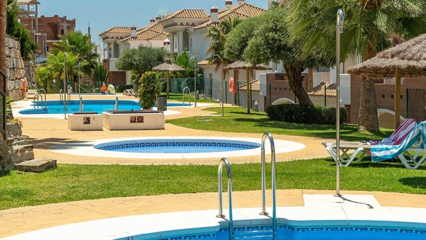 A pool area with multiple swimming pools, lounge chairs, and palm trees. - Modern, ground floor Casares Playa (Casares)
