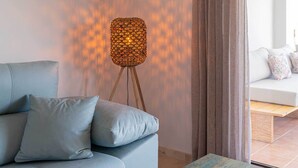 A modern living room with a light blue sofa, a decorative floor lamp, and a view through a window with curtains. - Modern, ground floor Casares Playa (Casares)
