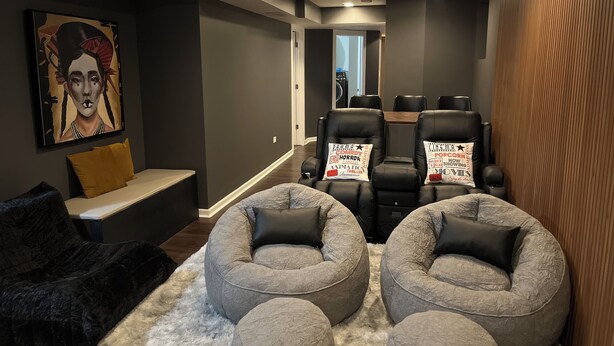 A modern home theater room with a sofa, two bean bag chairs, and a large screen.