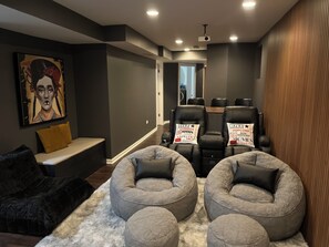 A modern home theater room with a sofa, two bean bag chairs, and a large screen. - Chic 2-bedroom apartment in historic Chicago neighborhood with theater, Wifi (Chicago)