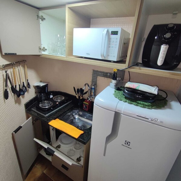 Une cuisine compacte équipée d’un four à micro-ondes, d’un petit réfrigérateur, d’une cuisinière et d’un évier.