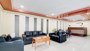 A modern lobby with two sofas, a wooden coffee table, and a reception desk.