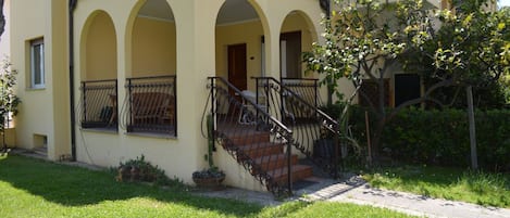 A two-story building with a balcony, arched windows, and a staircase with a railing.