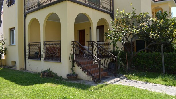 A two-story building with a yellow facade, arched windows, and a staircase with metal railings.