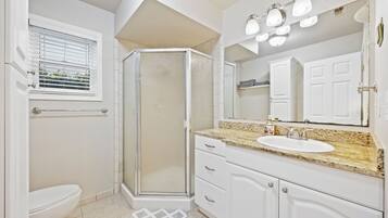 A bathroom with a toilet, shower, sink, and vanity.