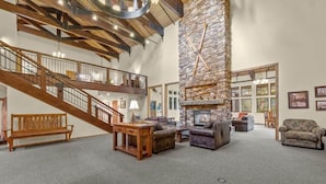 A spacious living area with a stone fireplace, wooden staircase, and comfortable seating. - The Meadows- Charmed Ski & Relax Studio (Kirkwood)