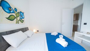 Ett hotellrum med en säng, en tavla, ett skrivbord och ett badrum som syns genom en öppen dörr.