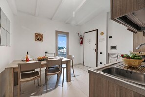 A modern kitchen with a wooden dining table, chairs, a sink, and a window with a view.
