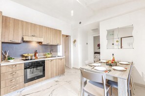 A modern kitchen with wooden cabinets, a built-in oven, and a dining area with a table set for two.