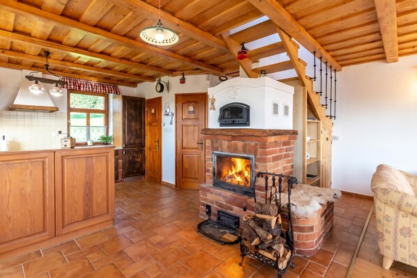Eine rustikale Küche mit Kamin aus Ziegelsteinen, Holzbalkendecke und einer Holztreppe.