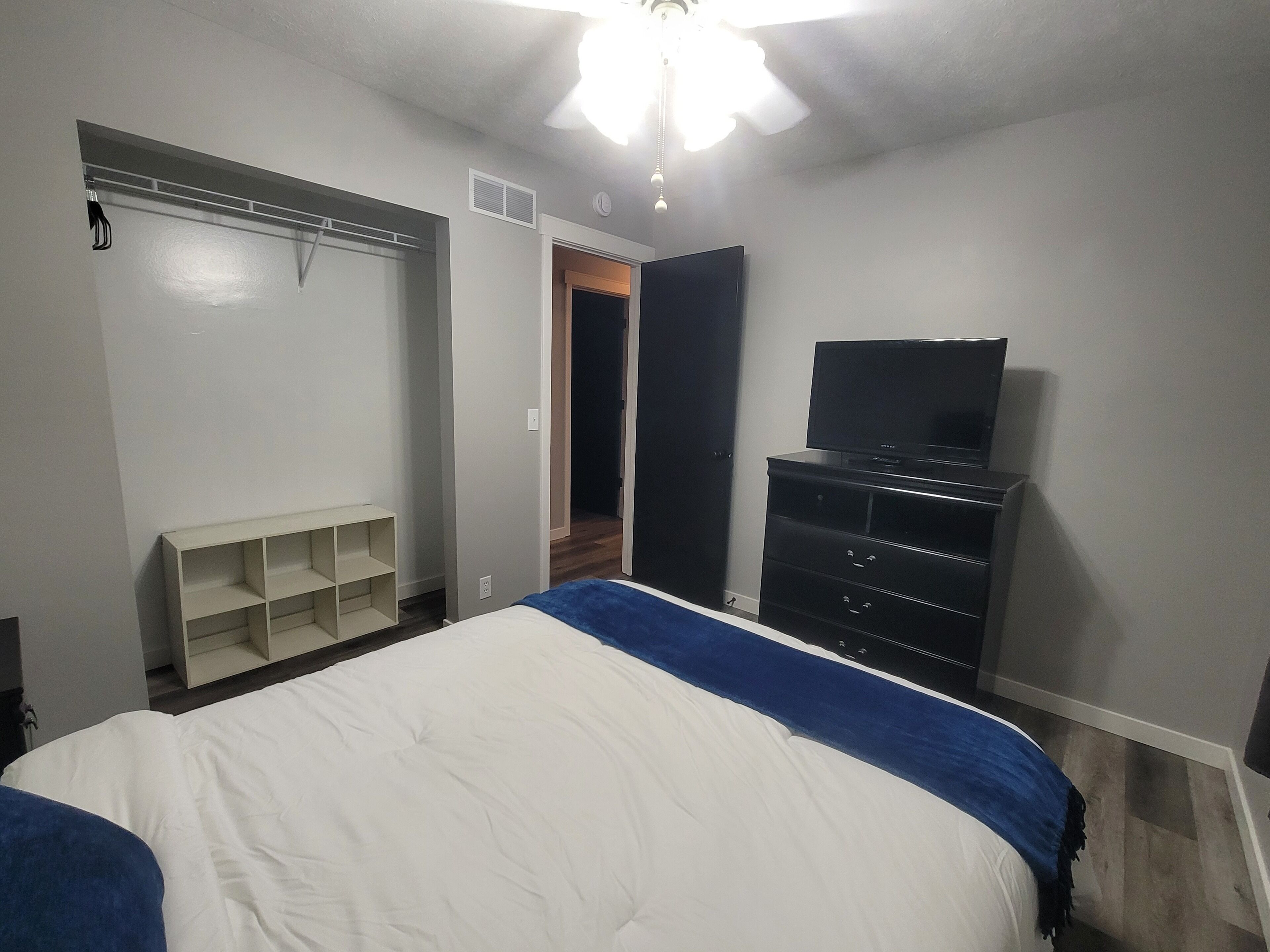 A bedroom with a bed, a TV on a dresser, and a walk-in closet.