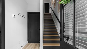 Una escalera de madera con barandillas negras que lleva a una puerta oscura.