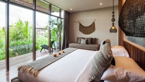 Ein modernes Schlafzimmer mit einem großen Bett, einer Couch und Blick auf Grünfläche.