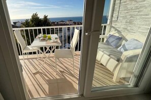 A balcony with a table set for breakfast, a wicker sofa, and a view of the sea. - Apartment with Incredible Sea Views and Balcony (Nerja)