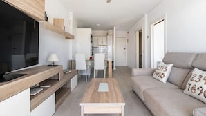 Un ambiente moderno e compatto con angolo cottura, zona pranzo e divano con cuscini decorativi.