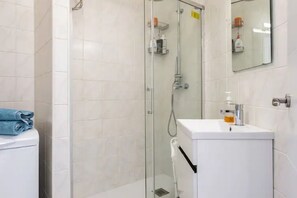 A modern bathroom with a glass-enclosed shower, a white sink with a soap dispenser, and a towel on the toilet. - Apartment with Incredible Sea Views and Balcony (Nerja)