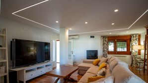 A modern living room with a flat-screen TV, a sofa, and a wooden coffee table. - Luxury Villa! Pool, Garden, and Jacuzzi. Granada (Albolote)