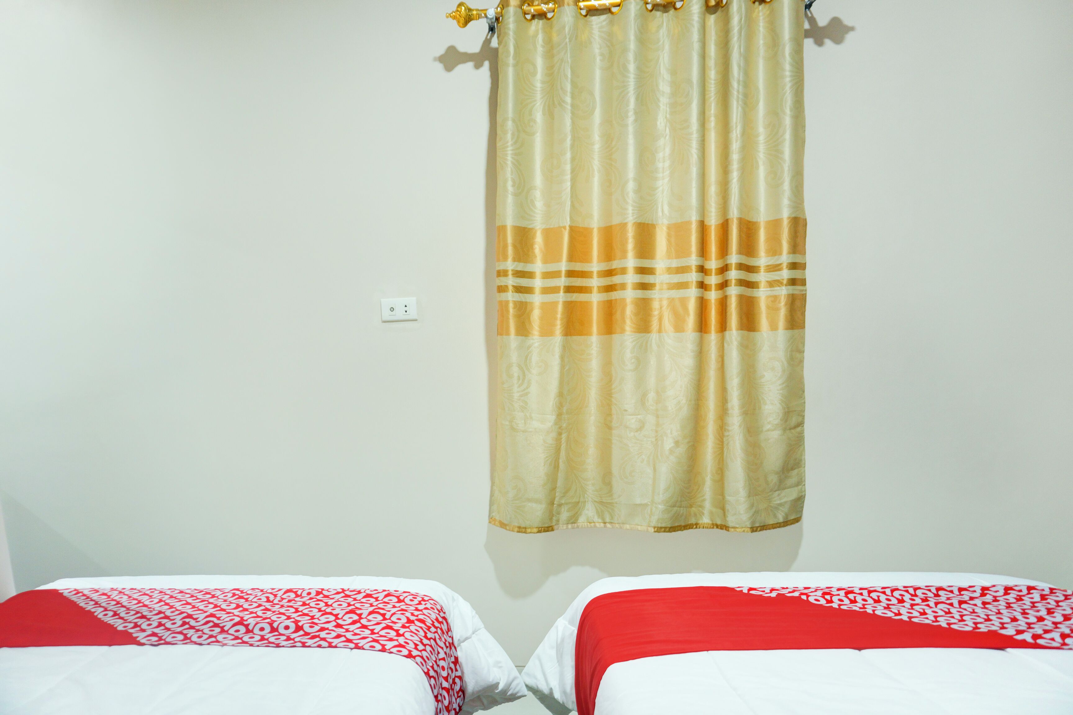 A hotel room with two beds, each with a red and white patterned bedspread.
