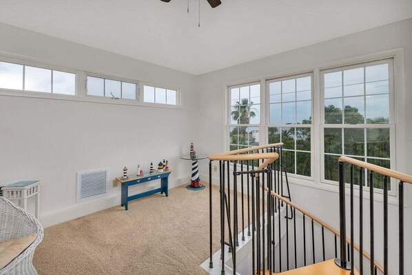 A spacious room with a high ceiling, large windows, a wooden staircase, and a small blue table with toys. - Large Family Home, Pool, Pet Friendly and Steps from the Beach (Jekyll Island)