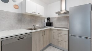 Una cocina moderna con armarios blancos, un refrigerador de acero inoxidable, un microondas y un lavavajillas.