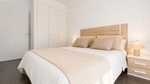 Un dormitorio con cama, mesitas de noche, armario y lámpara colgante.
