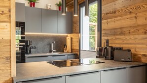 Eine moderne Küche mit grauen Schränken, einem schwarzen Herd und einer Holzwand.