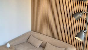 Een moderne kamer met een bank, een klein rond tafeltje en een lamp.