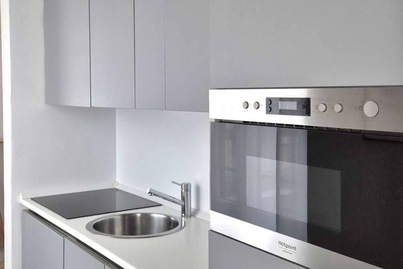 Een moderne keuken met een roestvrijstalen spoelbak, een zwart inductiekookplaat en een inbouwoven.