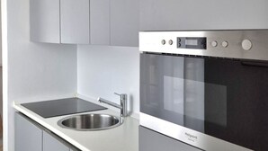 Een moderne keuken met een roestvrijstalen spoelbak, een zwart inductiekookplaat en een inbouwoven.