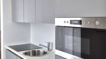 Een moderne keuken met een roestvrijstalen spoelbak, een zwart inductiekookplaat en een inbouwoven.