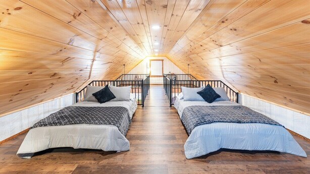 Ein gemütliches Schlafzimmer im Dachgeschoss mit zwei Betten, Holzbalkendecken und einem Oberlicht.
