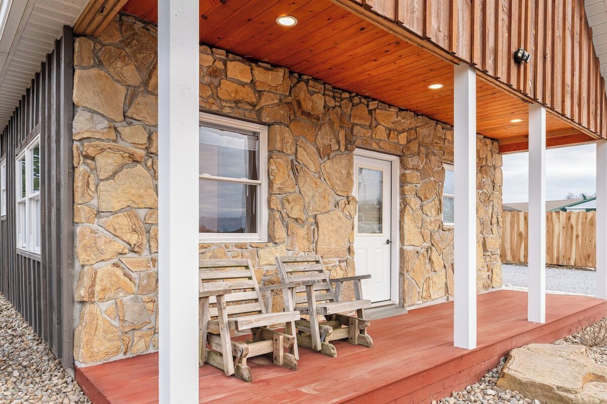 A stone building with a porch, wooden benches, and a door.