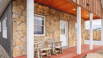 A stone building with a porch, wooden benches, and a door.