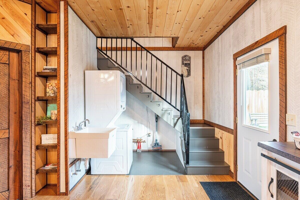 A staircase leading to a kitchen with a sink and shelves.