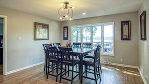 A dining area with a large table and chairs, a ceiling light fixture, and framed artwork on the walls. - Amazing Views, Huge Game Room, Dock, Deck, Sleeps 16, Free Kayaks! (Hot Springs Village)