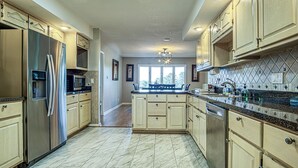 A spacious kitchen with a large island, stainless steel appliances, and a tiled backsplash. - Amazing Views, Huge Game Room, Dock, Deck, Sleeps 16, Free Kayaks! (Hot Springs Village)
