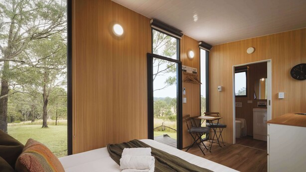 A bedroom with a large bed, a dining area, and a view of the outdoors. - One-Gaea by Tiny Away (Rainbow Flat)