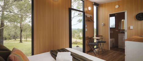 A bedroom with a large bed, a dining area, and a view of the outdoors.