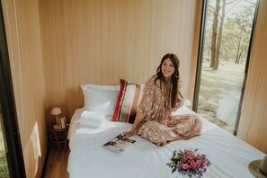 A room with a bed, a nightstand, a lamp, and a window.
