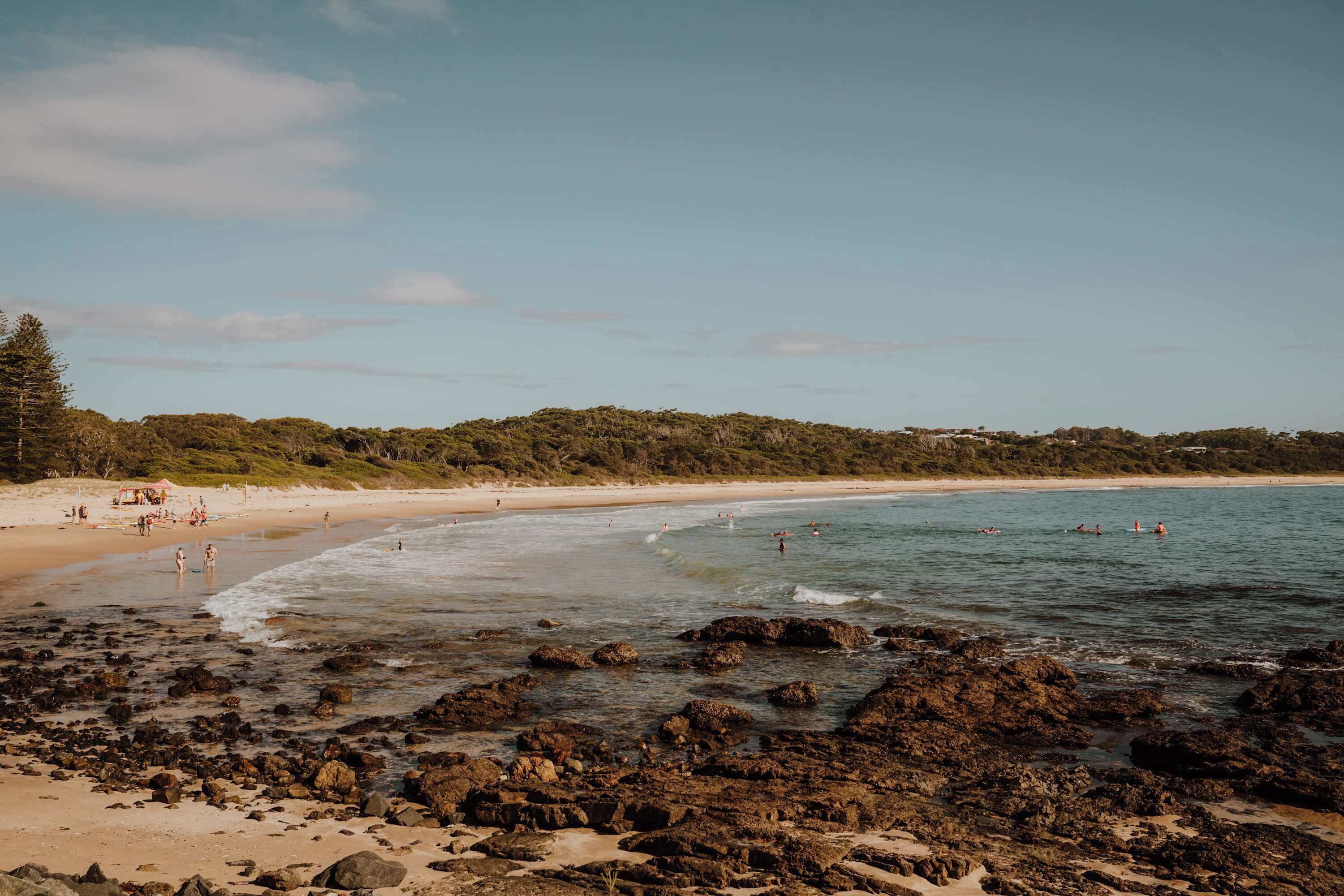 A beach with rocky shoreline, clear water, and a sandy beach.