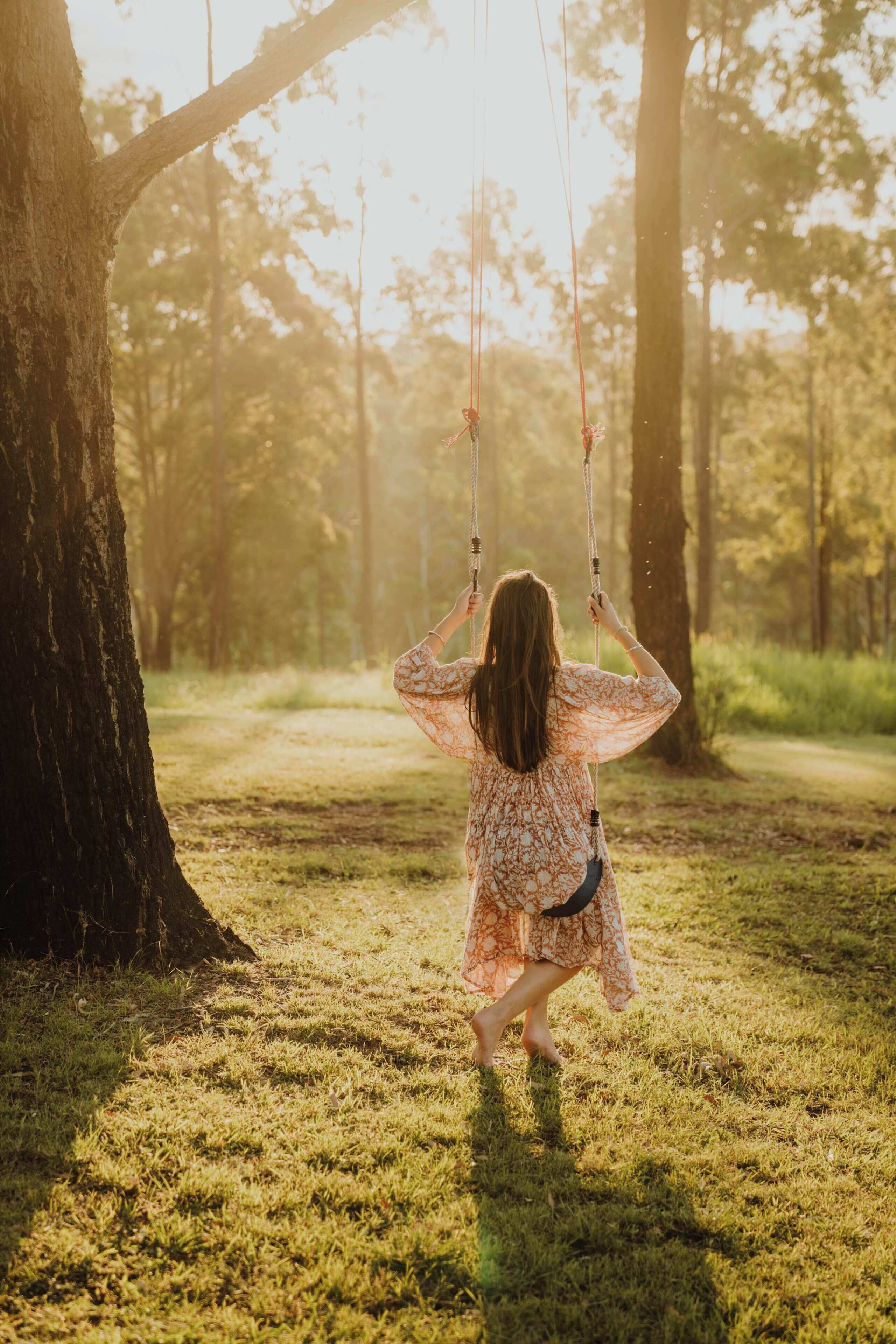 A person swinging on a rope swing in a wooded area.
